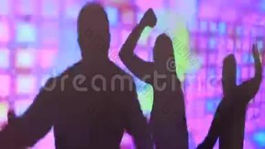 派对期间，在夜总会的彩屏上跳舞的男女剪影。